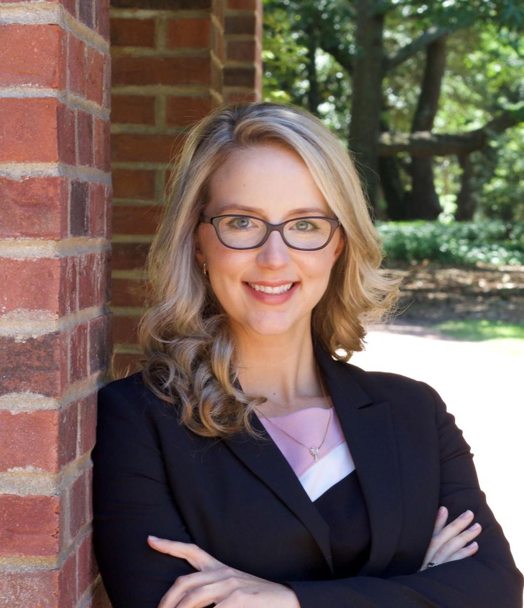 Ms. 玛丽莎·史密斯, a Caucasian female with long blond hair wears black rimmed glasses and a black suit jacket with a white shirt while smiling at the camera.